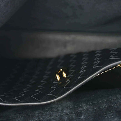 Close-up of black leather interior with patterned lining and gold zipper trim.