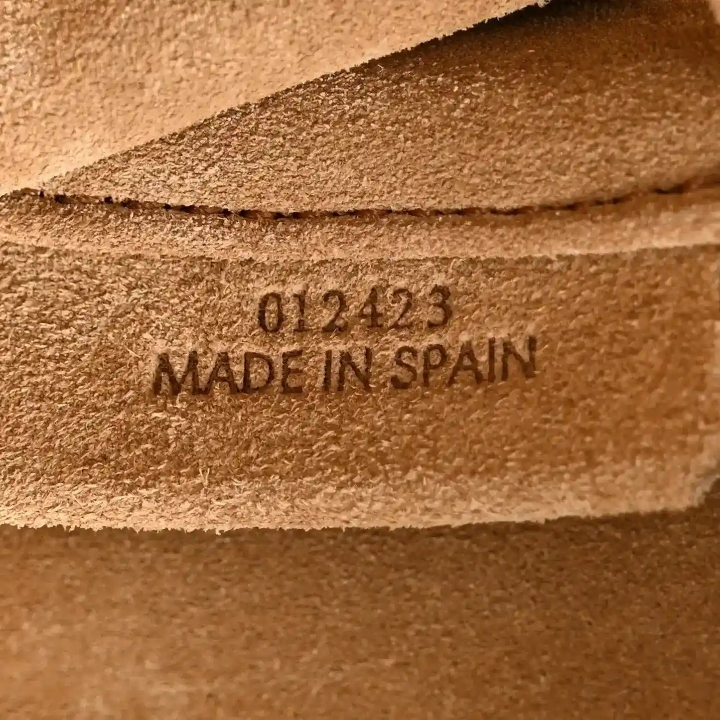 Tan leather clutch base label with code and “MADE IN SPAIN” stamp
