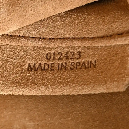 Tan leather clutch base label with code and “MADE IN SPAIN” stamp