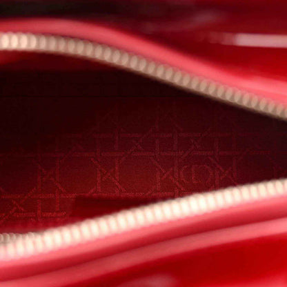 Red patent leather handbag interior lining with monogram pattern and zip trim.