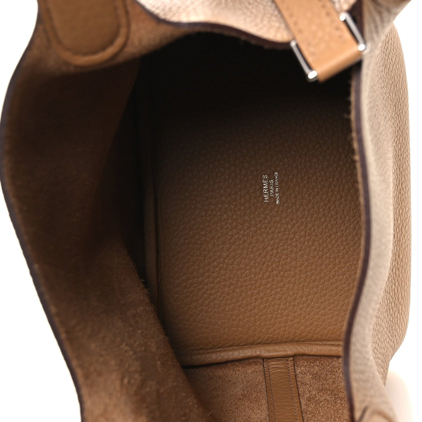 Tan leather interior of a bucket bag with brand stamp and open top lining.