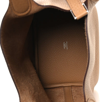Tan leather interior of a bucket bag with brand stamp and open top lining.