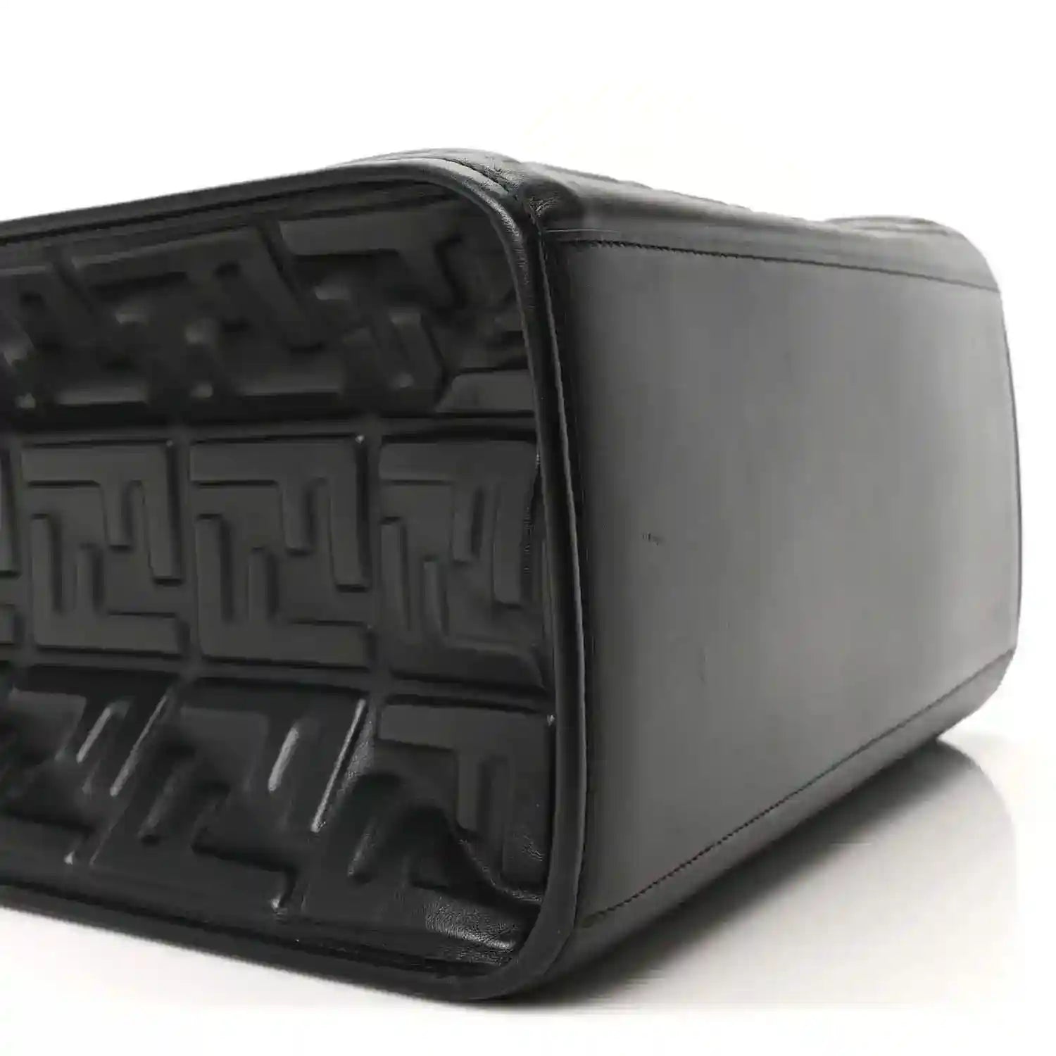 Black leather tote bag side view showing embossed interior and smooth exterior panel