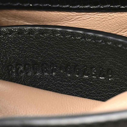 Stamped text on black leather interior panel of a mini Jackie handbag.