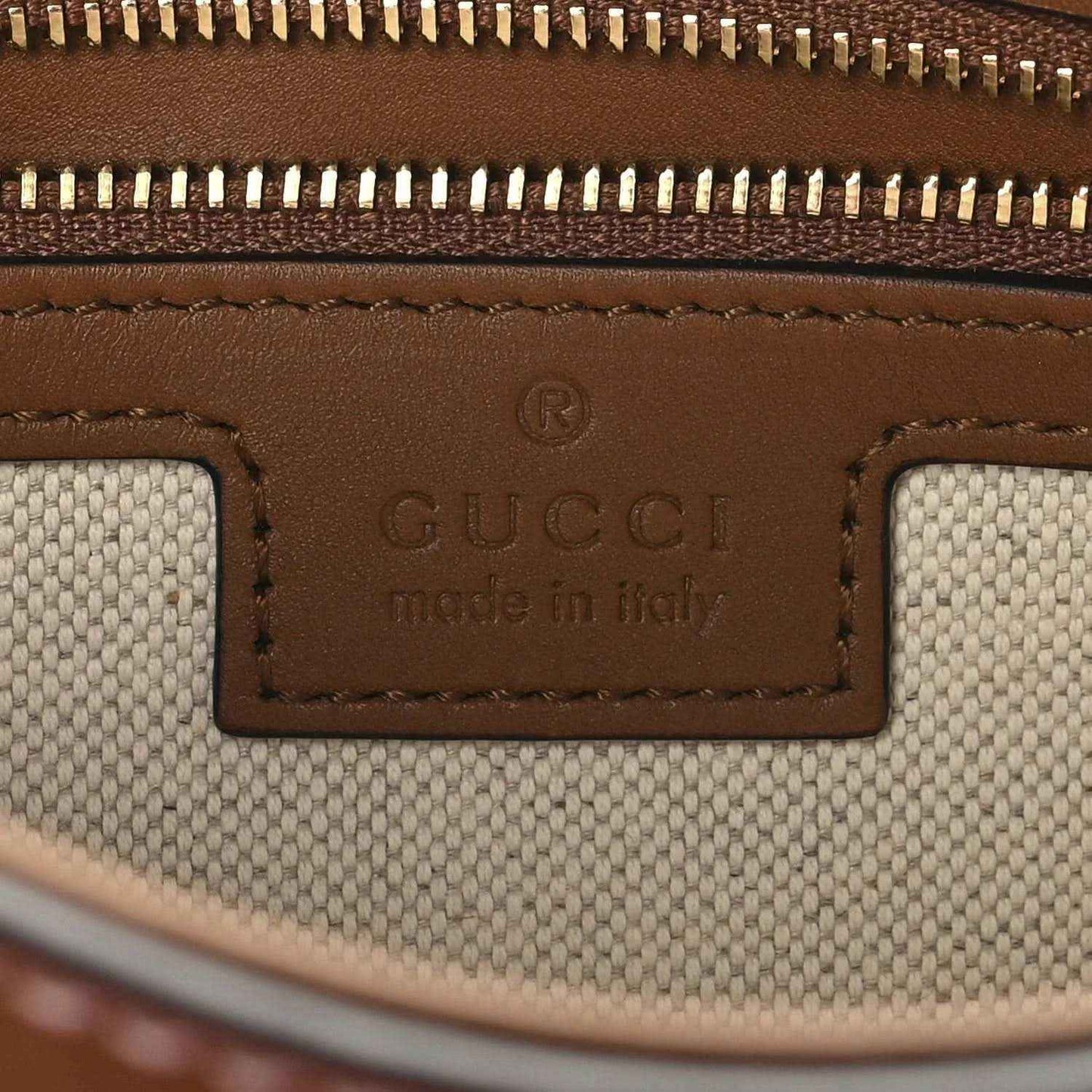 Gucci label reading “Made in Italy” on brown leather and beige canvas