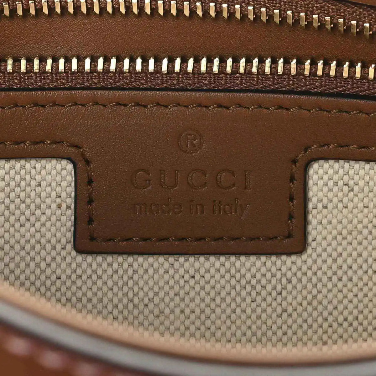 Gucci label reading “Made in Italy” on brown leather and beige canvas