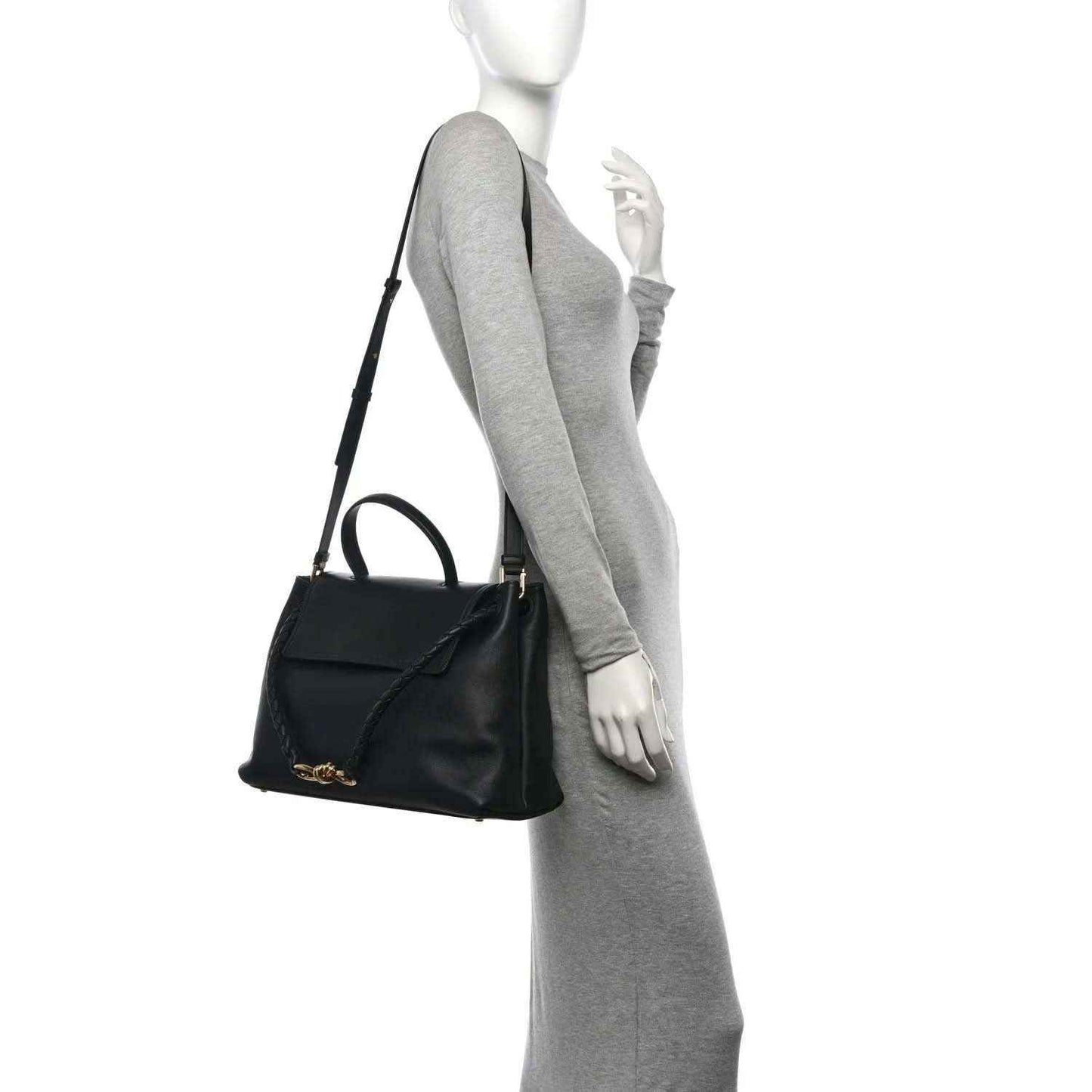 Black leather shoulder bag on model, short strap and gold accent hardware.