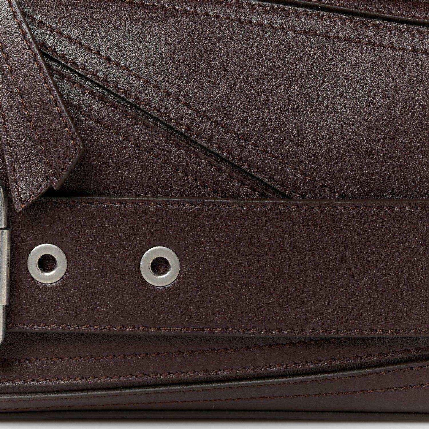 Front hardware and grommet holes on small biker bag, dark brown leather