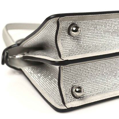 Small satchel front corner close-up with flap strap and round metal snap buttons
