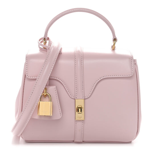 Pastel pink mini top-handle bag with flap front, gold lock detail, and shoulder strap