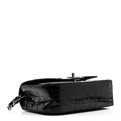 Black mini rectangular flap bag with glossy alligator texture and chain strap clasp.