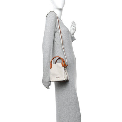 Loro Piana micro bale bag on model, natural canvas with tan leather strap and handles.