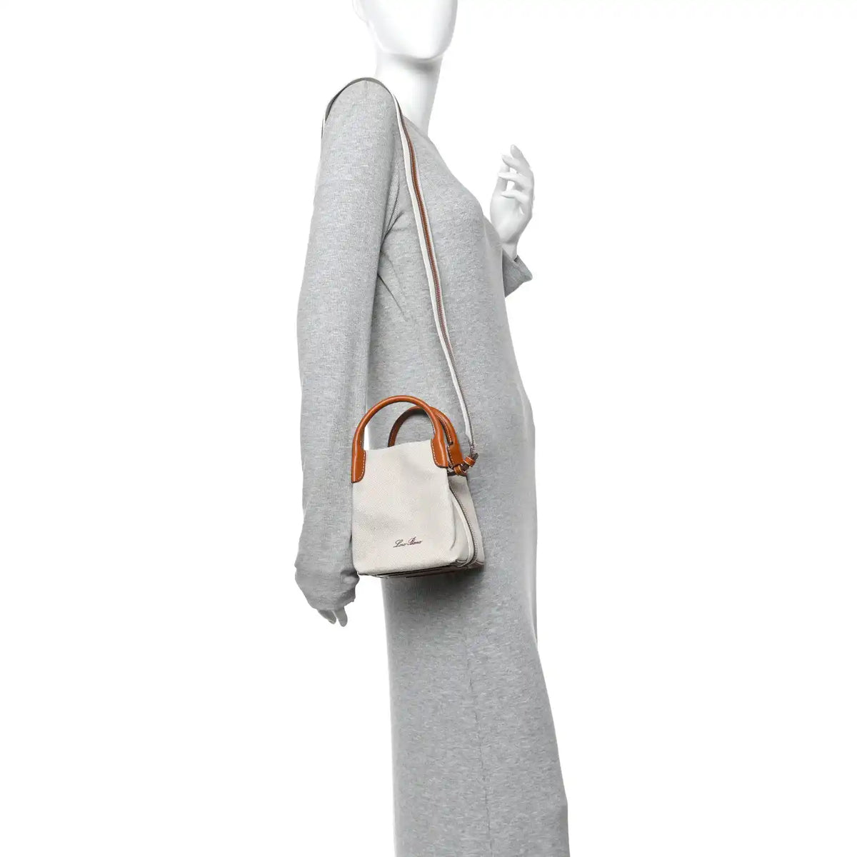 Loro Piana micro bale bag on model, natural canvas with tan leather strap and handles.