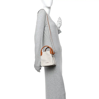 Loro Piana micro bale bag on model, natural canvas with tan leather strap and handles.