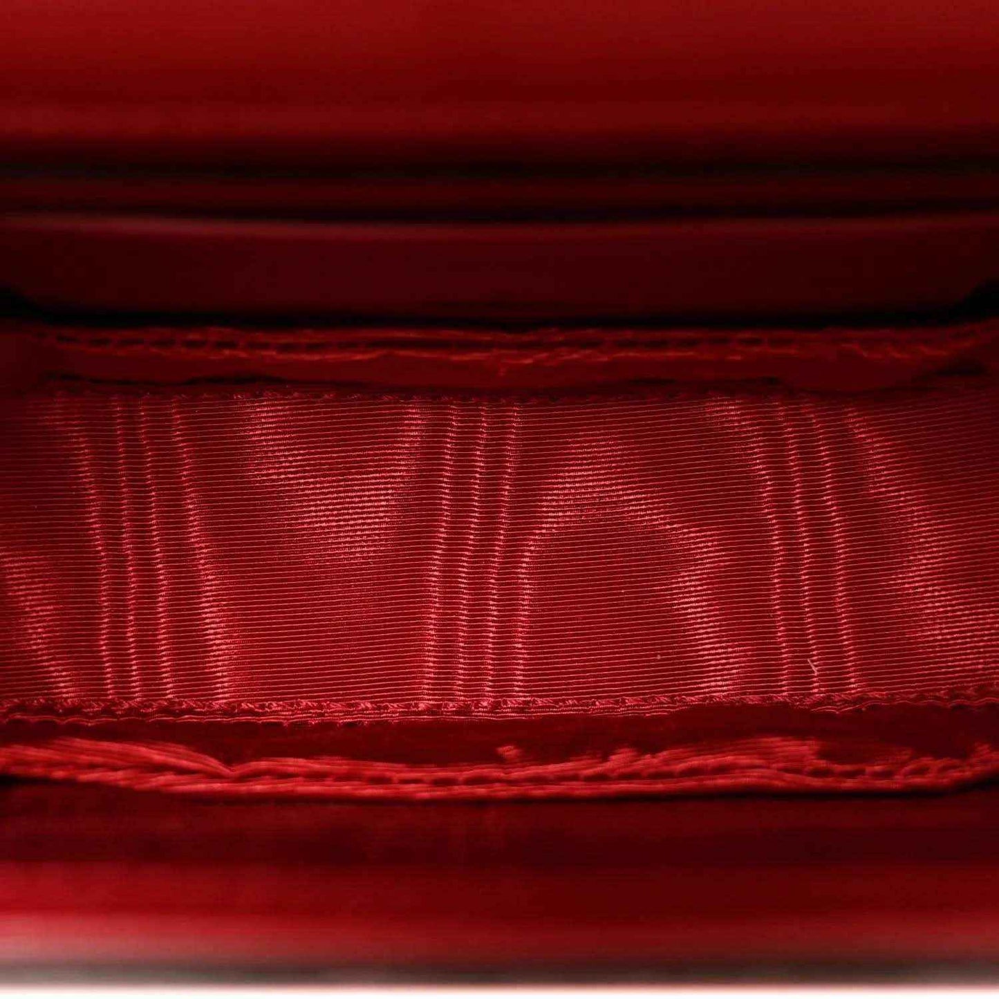 Red satin-like lining inside flap with stitched edge and seam detail.
