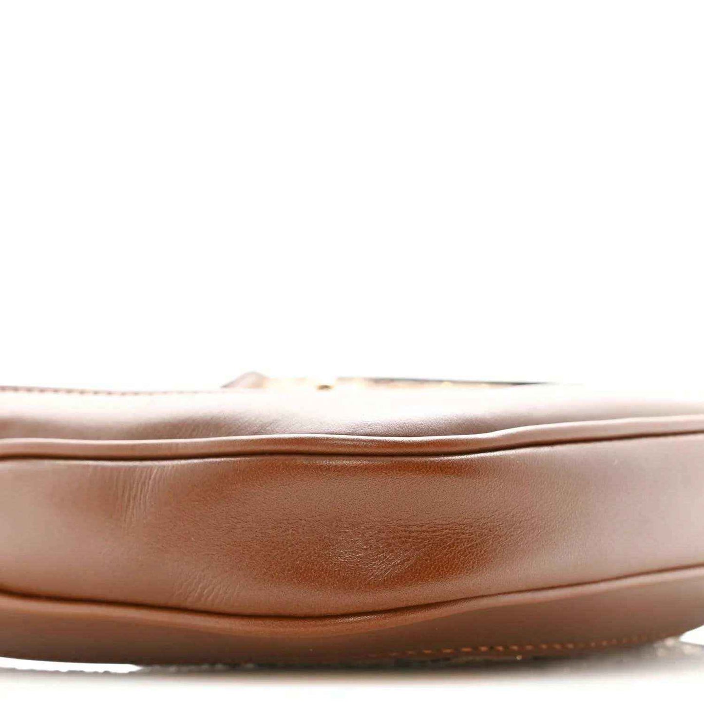 Mini hobo bag side panel close-up in tan leather with subtle creasing and stitched edge