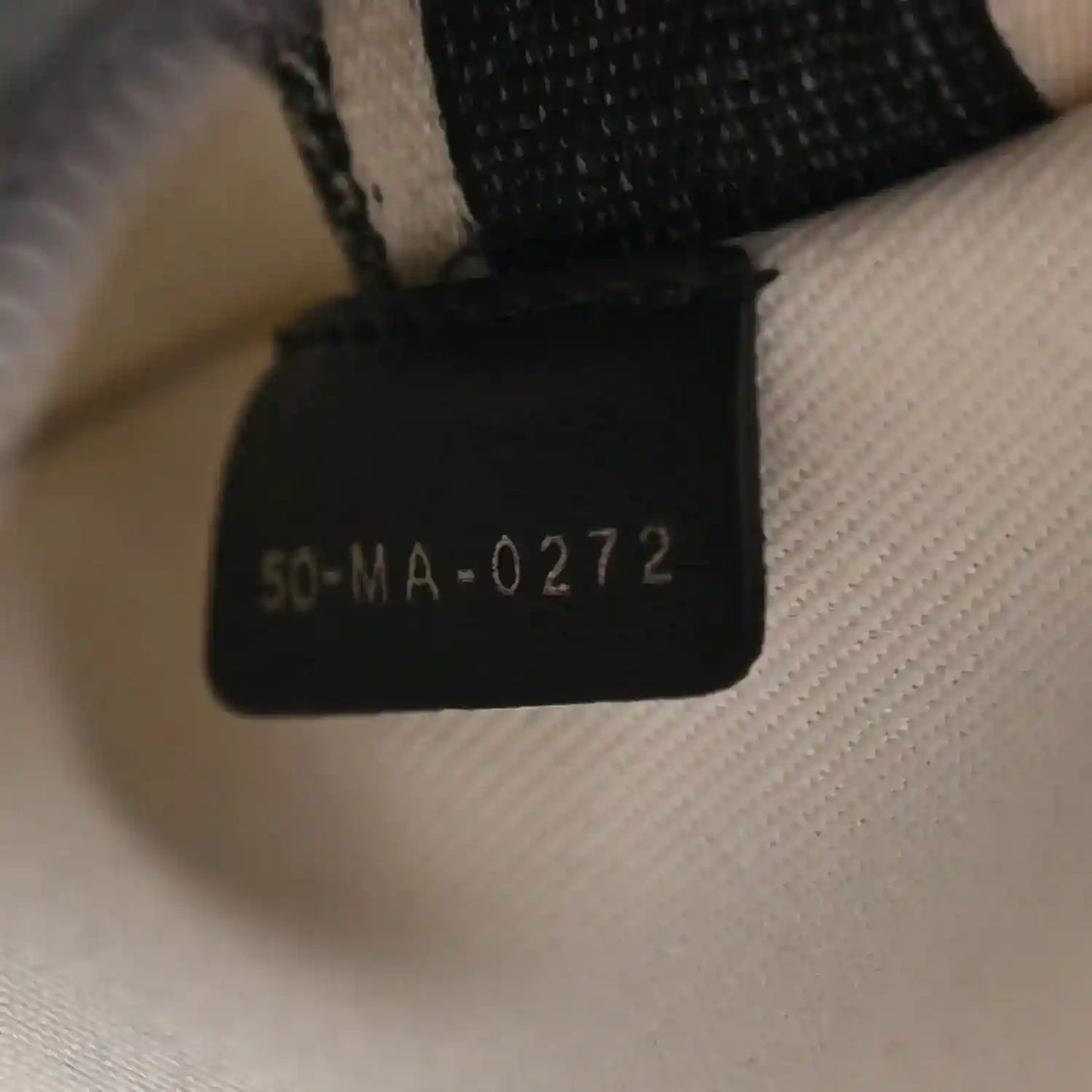Black fabric size tag reading '50-MA-0272' on houndstooth canvas bag