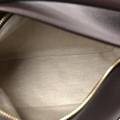 Dark leather bag interior with textured lining and gold-tone zipper trim