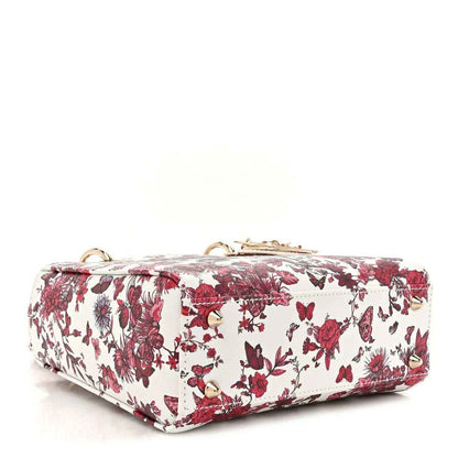 White and red floral handbag with top handle and structured flap front, gold-tone details