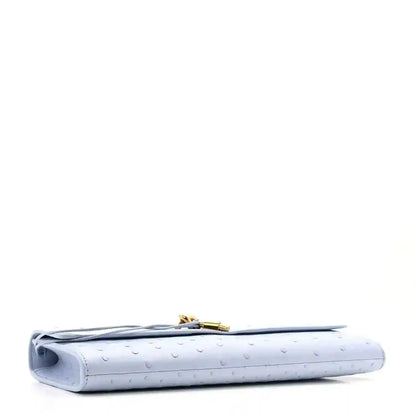 Light blue ostrich leather clutch bag corner detail with gold clasp and handle