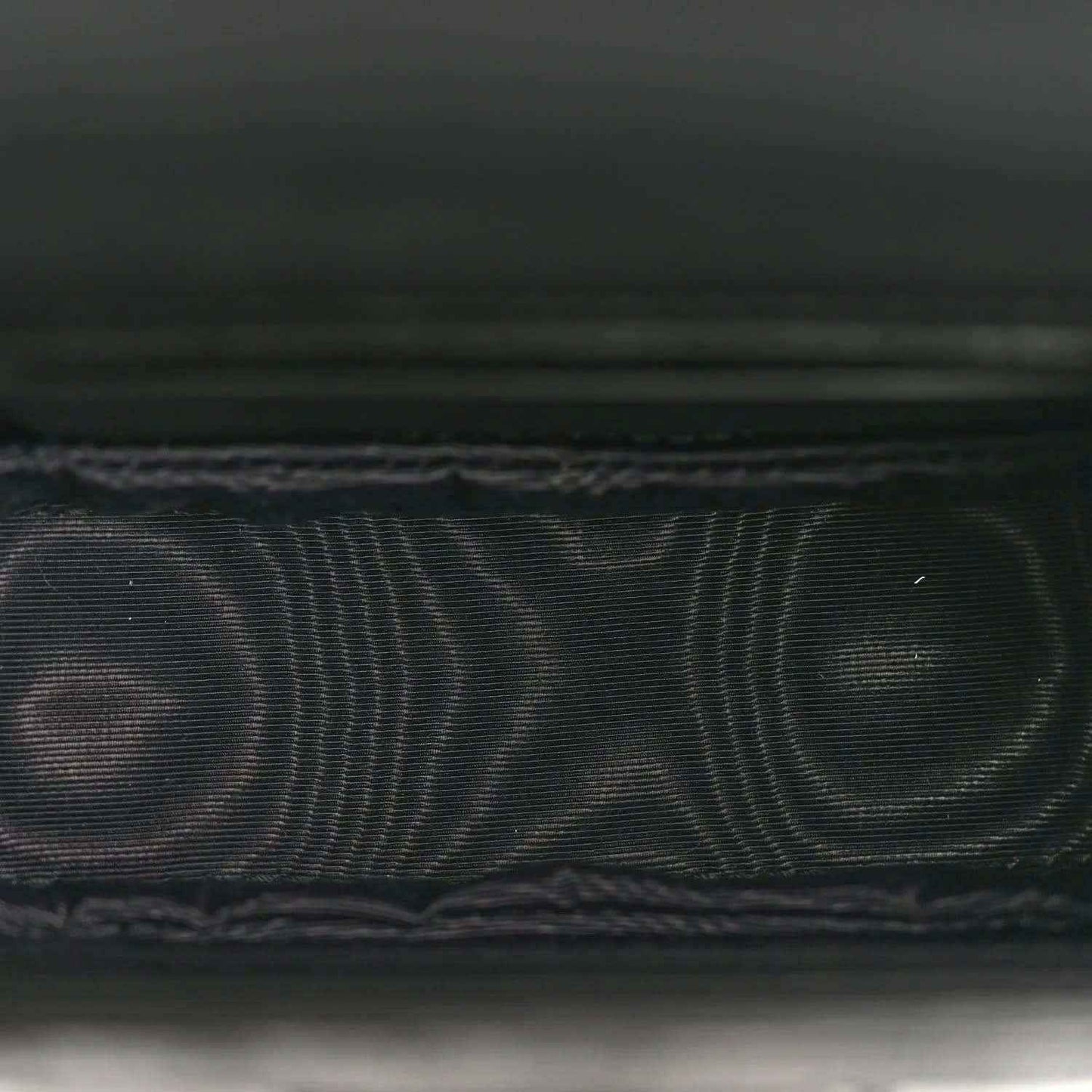 Black embossed leather detail with fine grid texture and stitched edge