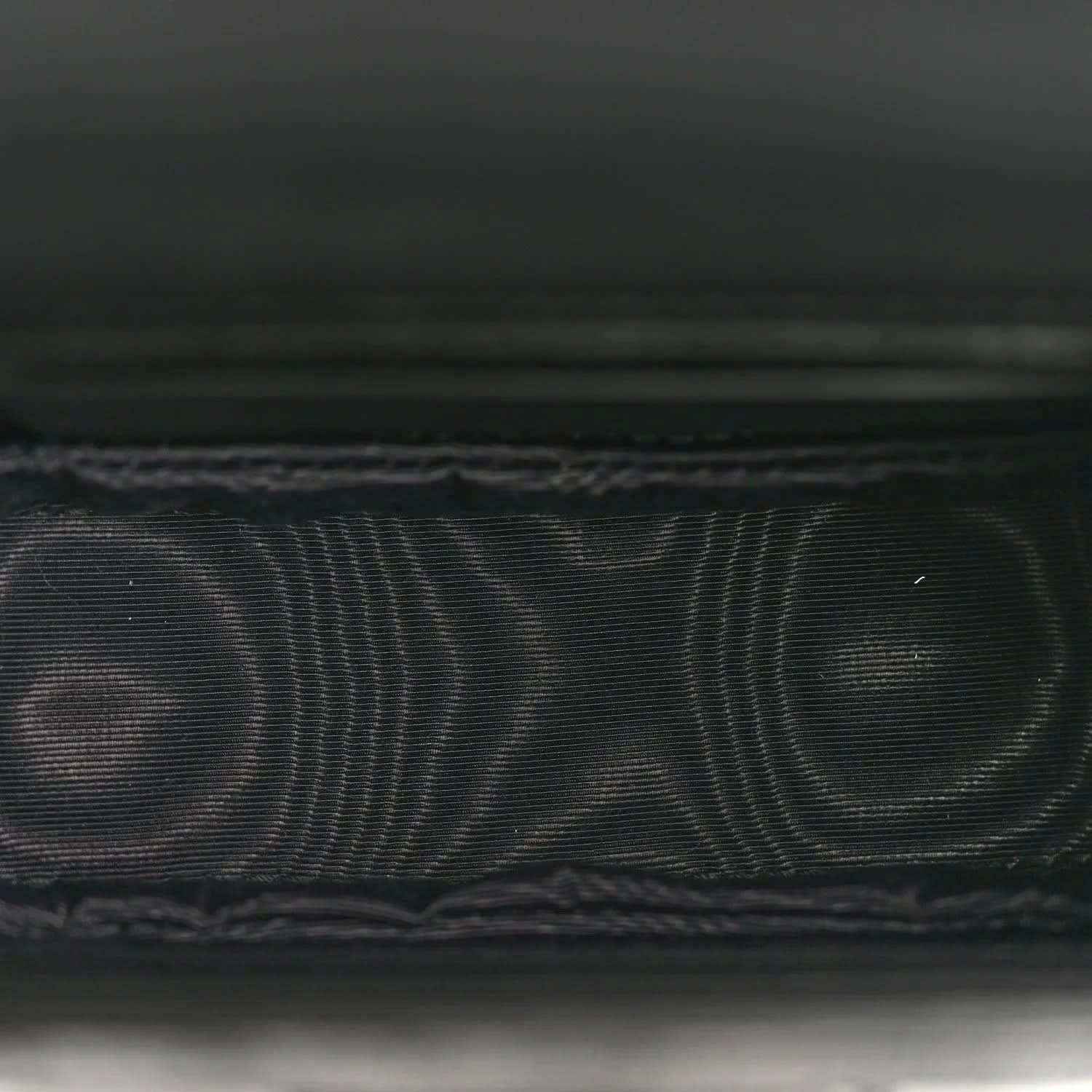 Black embossed leather detail with fine grid texture and stitched edge