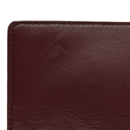 Burgundy leather clutch front panel close-up with smooth grain and stitched border