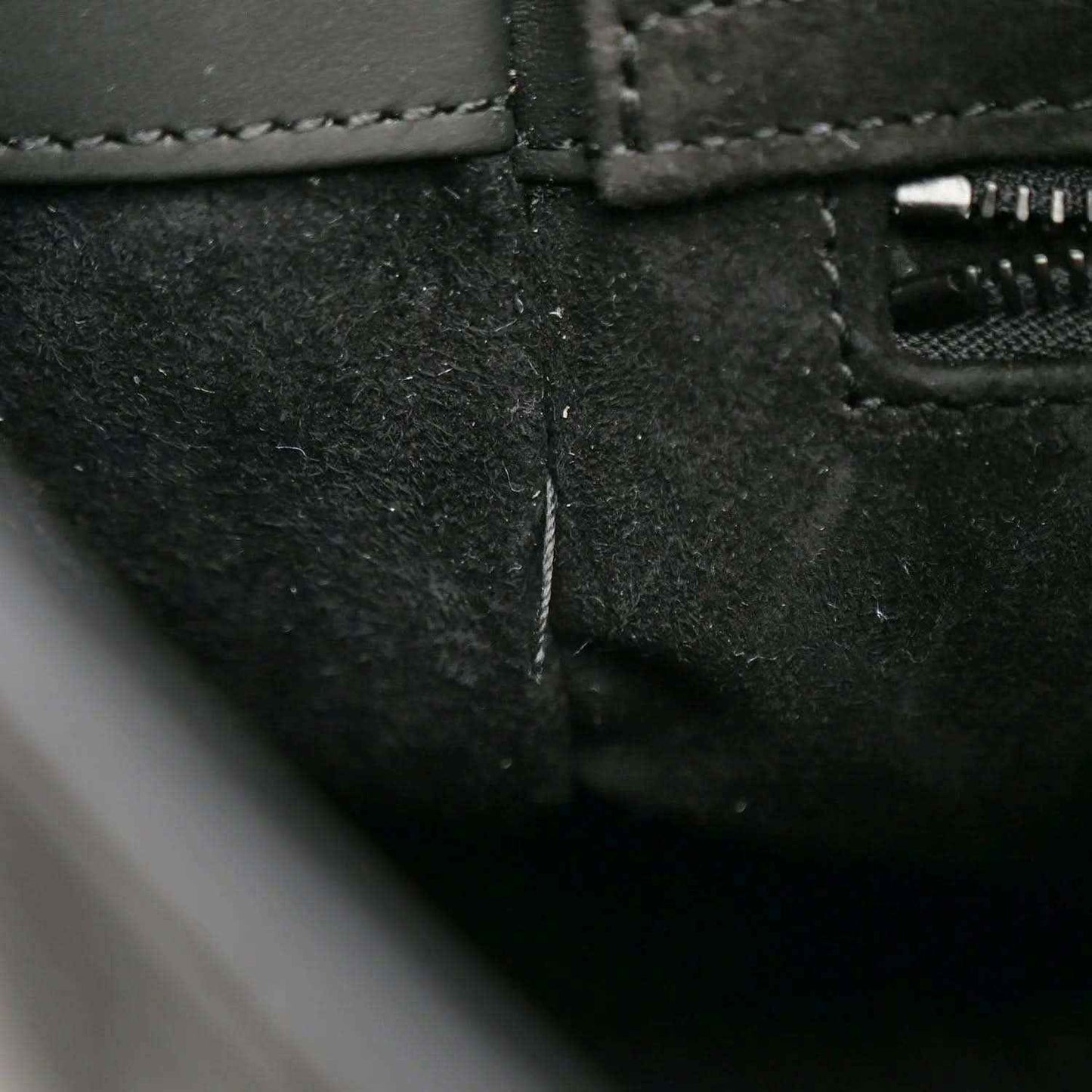 Black handbag close-up of stitched seam and zipper opening on the side panel