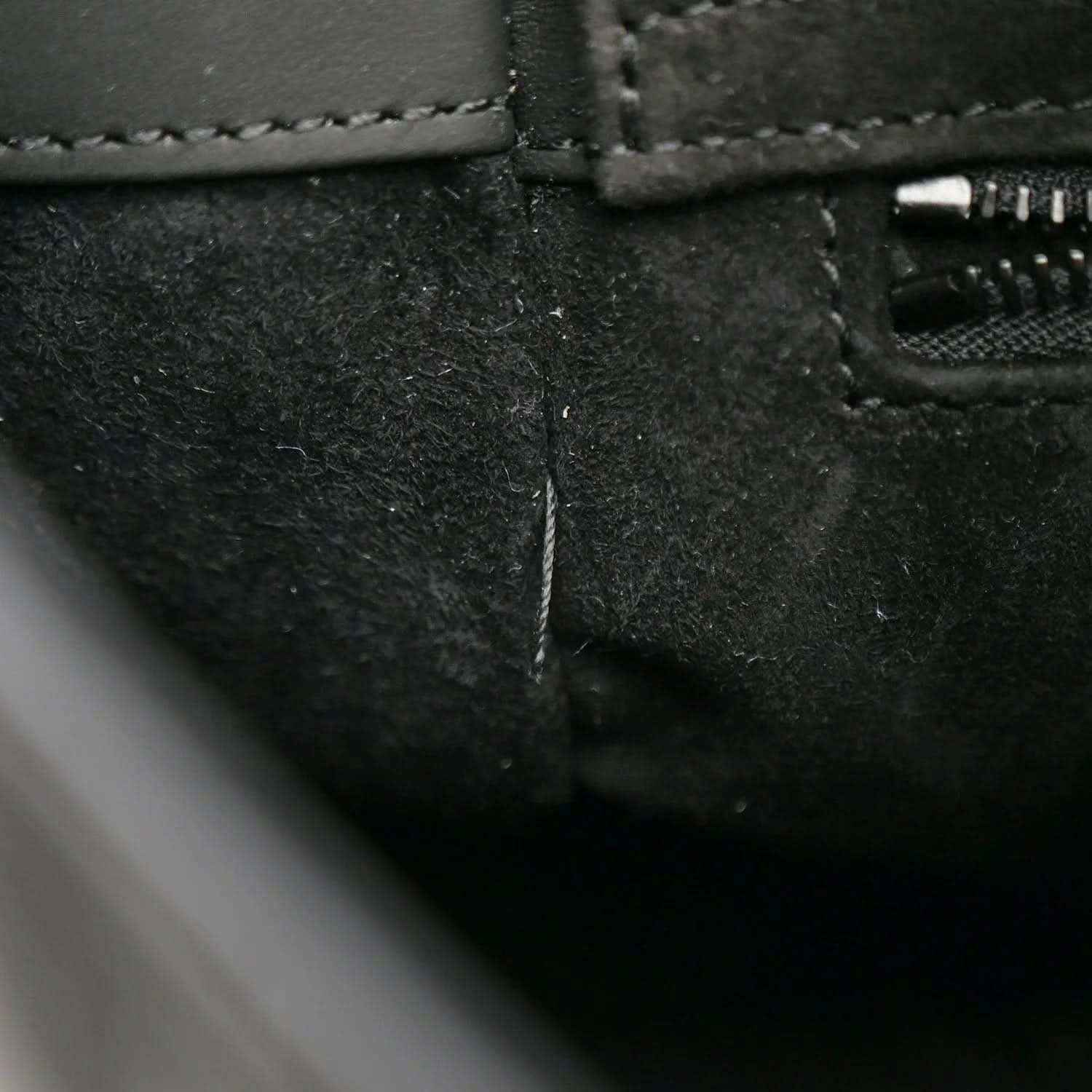 Black handbag close-up of stitched seam and zipper opening on the side panel