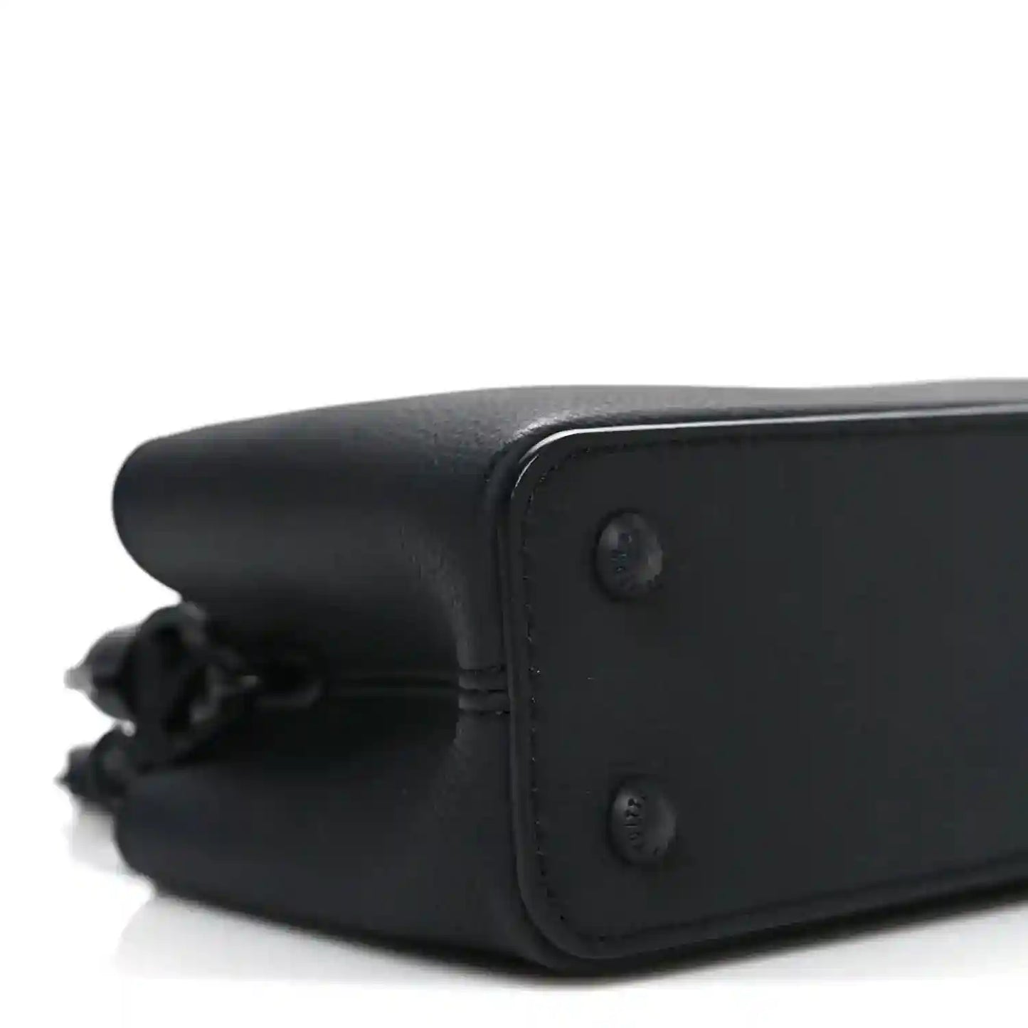 Mini black leather handbag corner with stitched edge and button detail.
