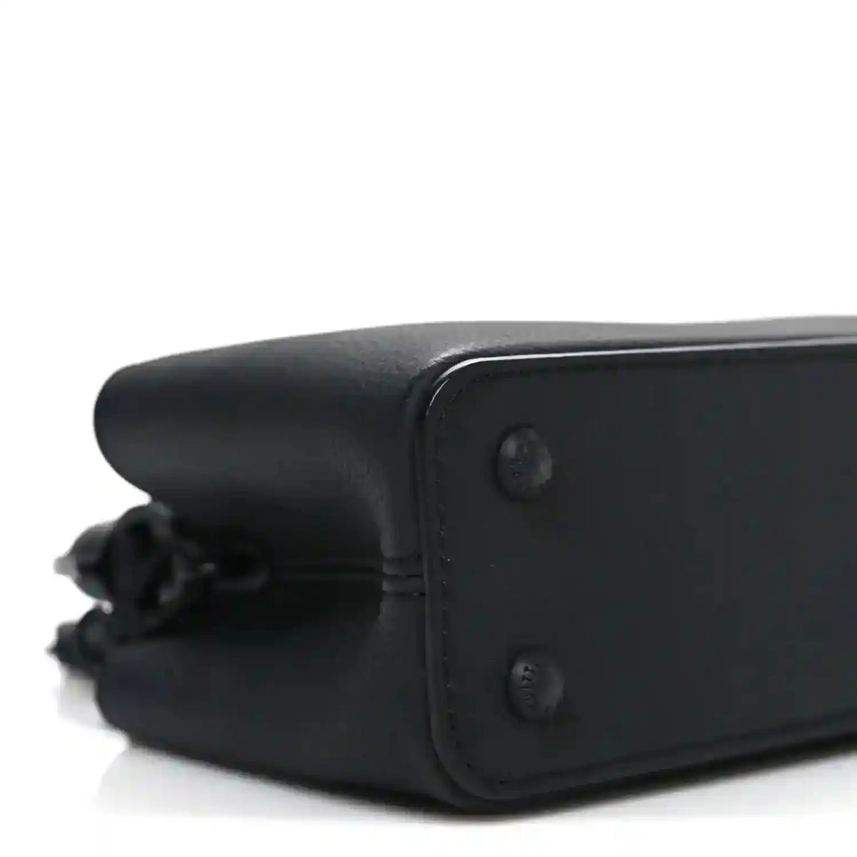Mini black leather handbag corner with stitched edge and button detail.