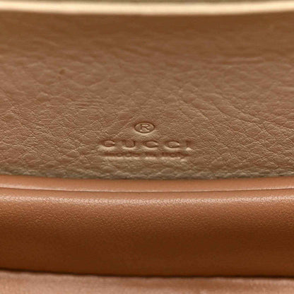 Embossed designer logo on leather base of a white mini handbag