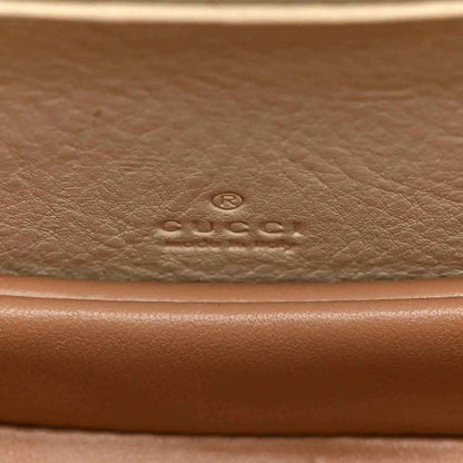 Embossed designer logo on leather base of a white mini handbag