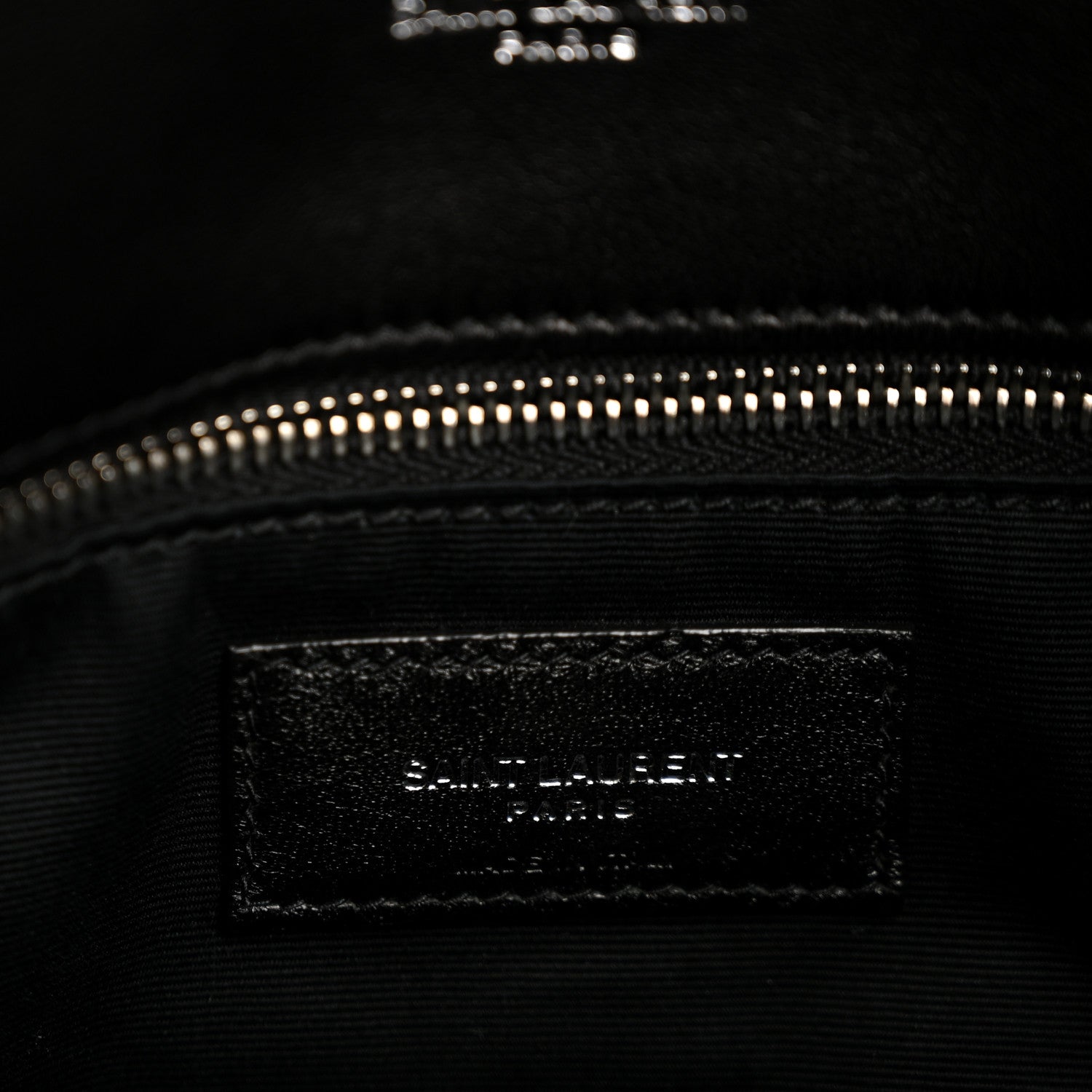Black interior pocket of quilted lambskin satchel with zipper at top edge