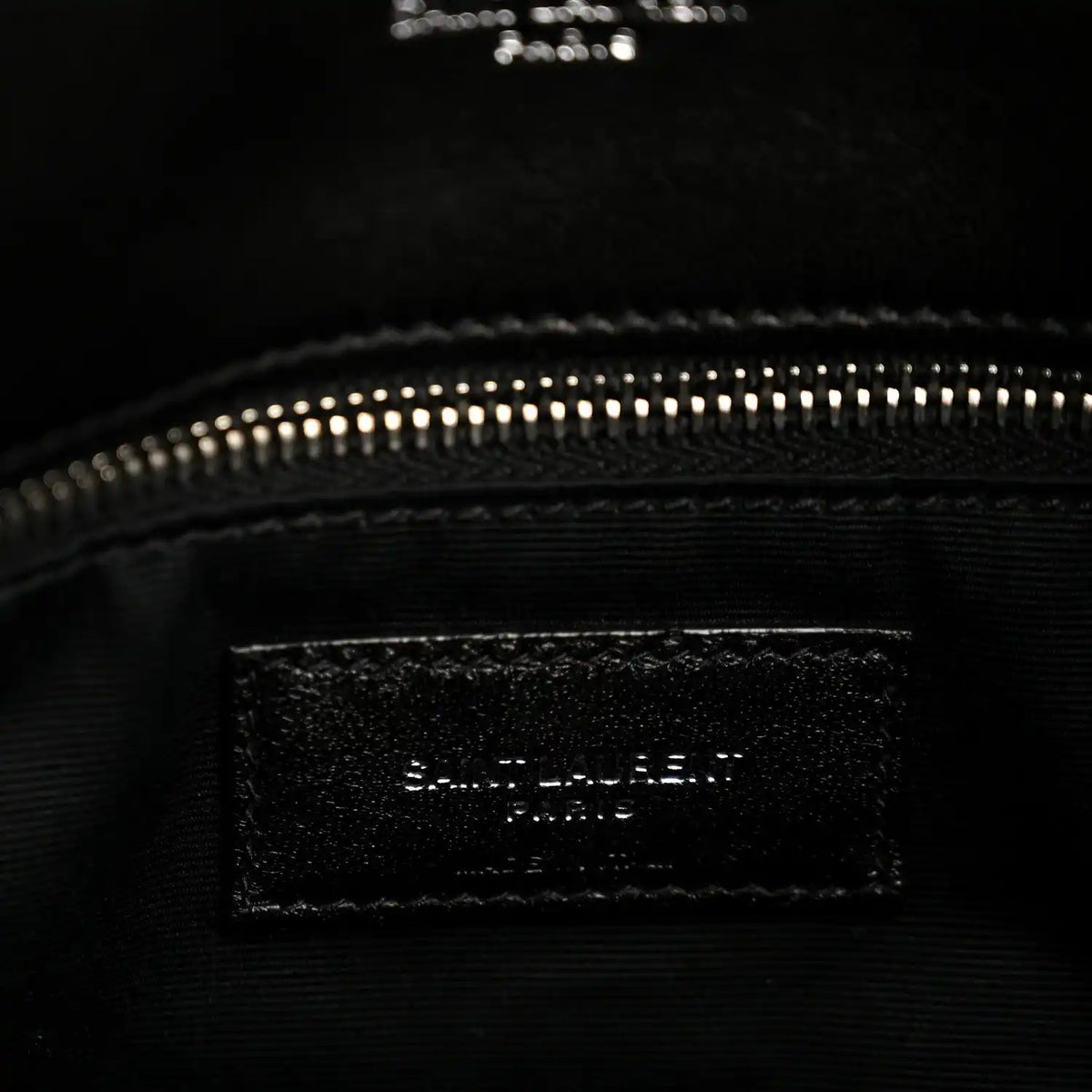 Black interior pocket of quilted lambskin satchel with zipper at top edge