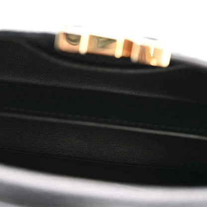 Close-up of black leather bag edge with gold-tone Louis Vuitton logo hardware