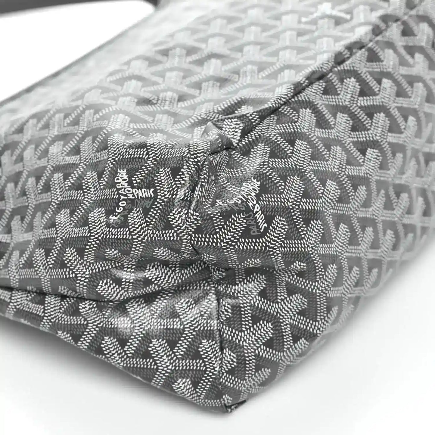 Grey coated canvas bag corner with repeating pattern and logo patch