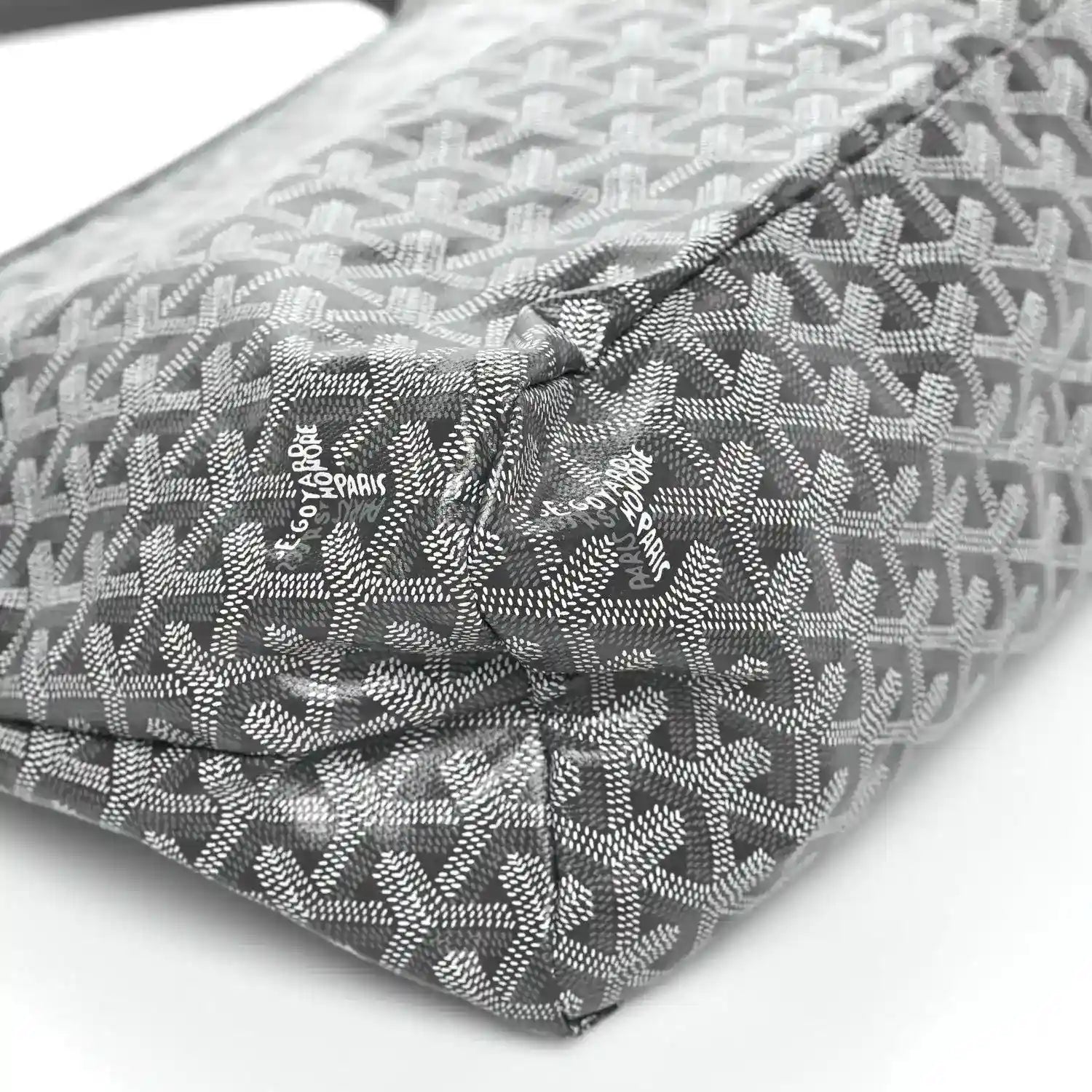Grey coated canvas bag corner with repeating pattern and logo patch