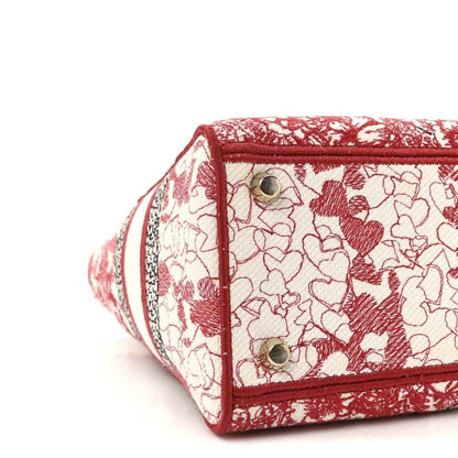 Handbag front pocket with red piping, floral embroidered canvas, and two silver snaps