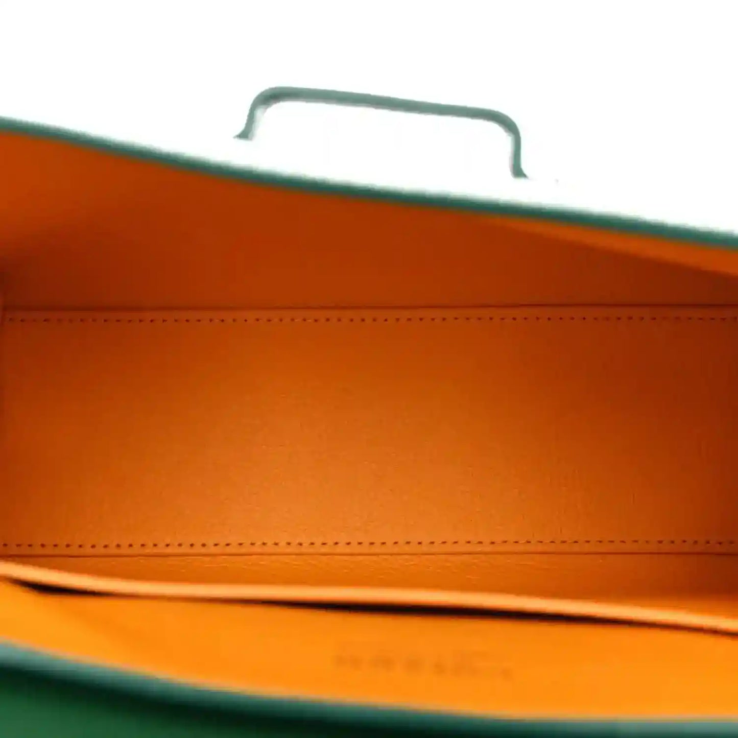 Orange-lined interior of the mini bag with green edge trim and stitching detail
