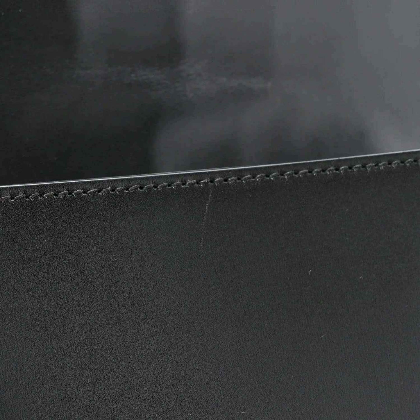Black leather messenger bag edge with contrast stitching and smooth calfskin texture