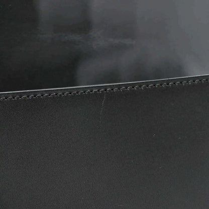 Black leather messenger bag edge with contrast stitching and smooth calfskin texture