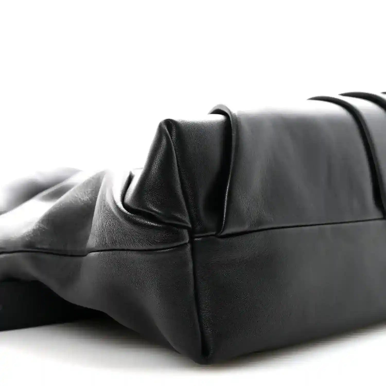 Black leather tote bag corner with structured base and folded side panel