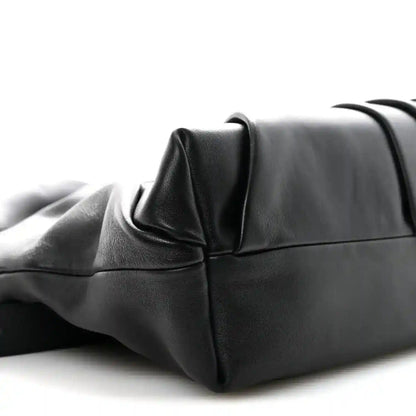 Black leather tote bag corner with structured base and folded side panel