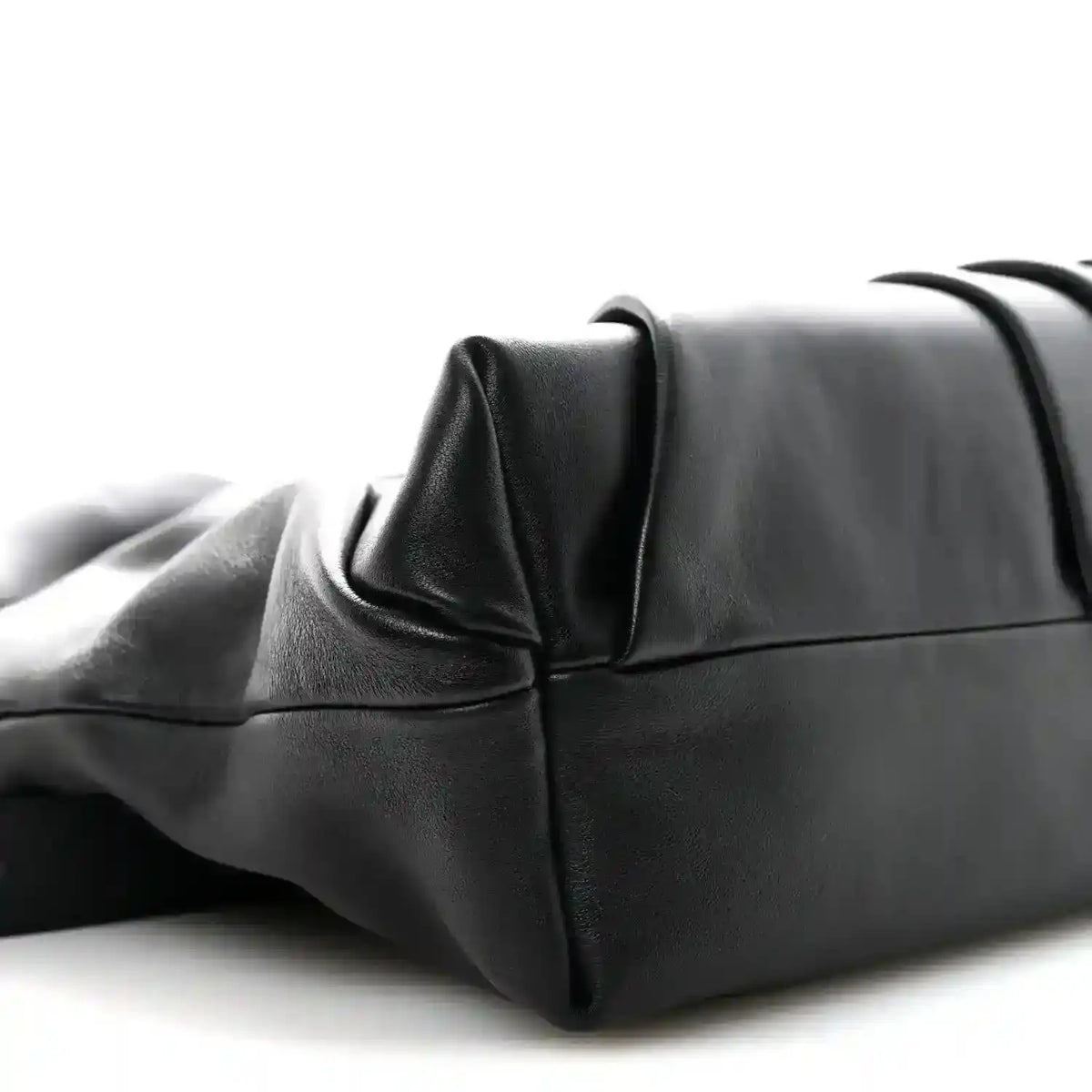 Black leather tote bag corner with structured base and folded side panel