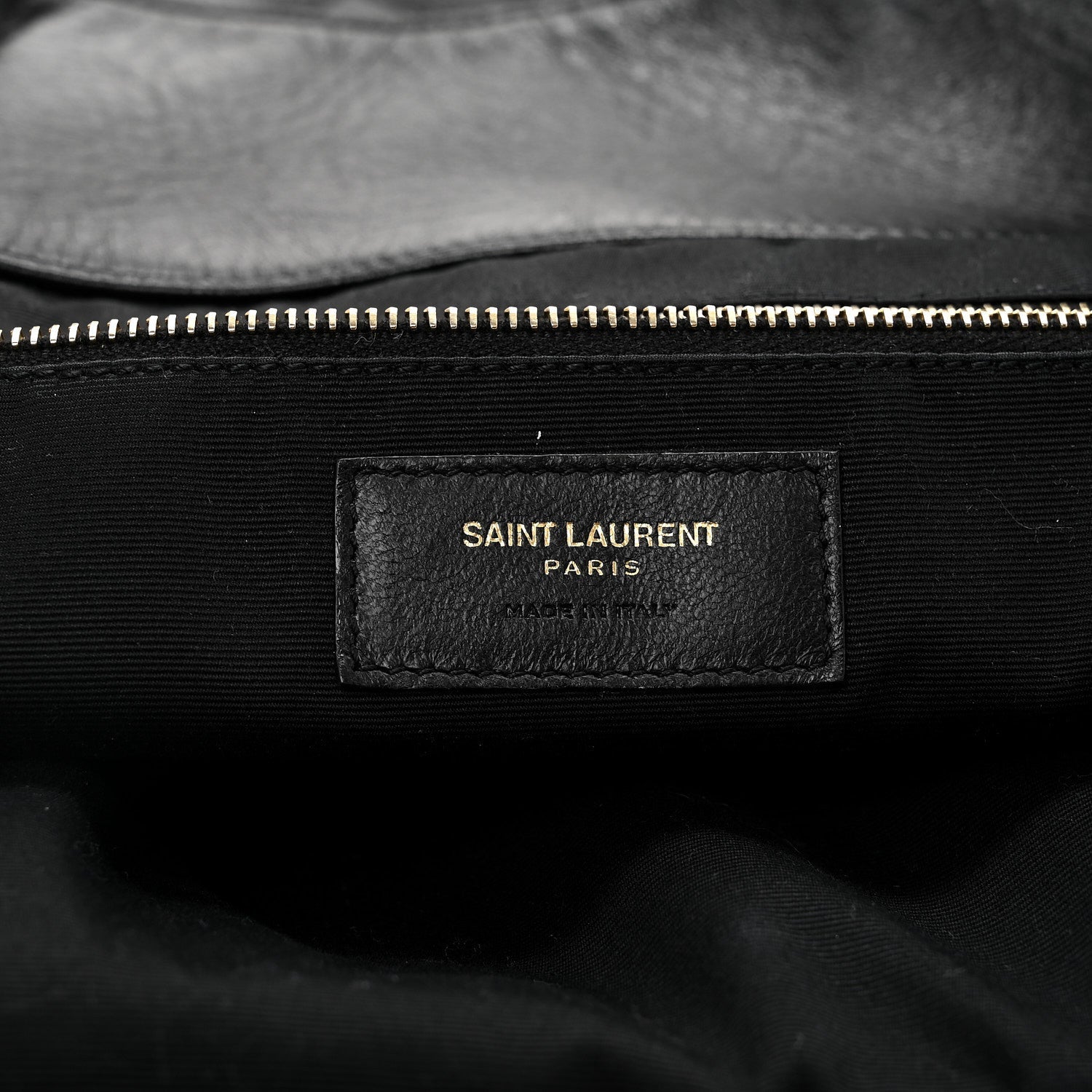Black fabric label with gold zipper edge and “SAINT LAURENT PARIS” text