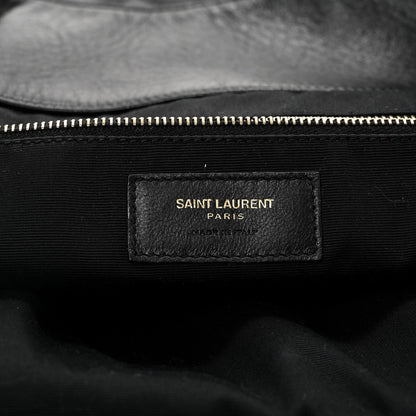 Black fabric label with gold zipper edge and “SAINT LAURENT PARIS” text