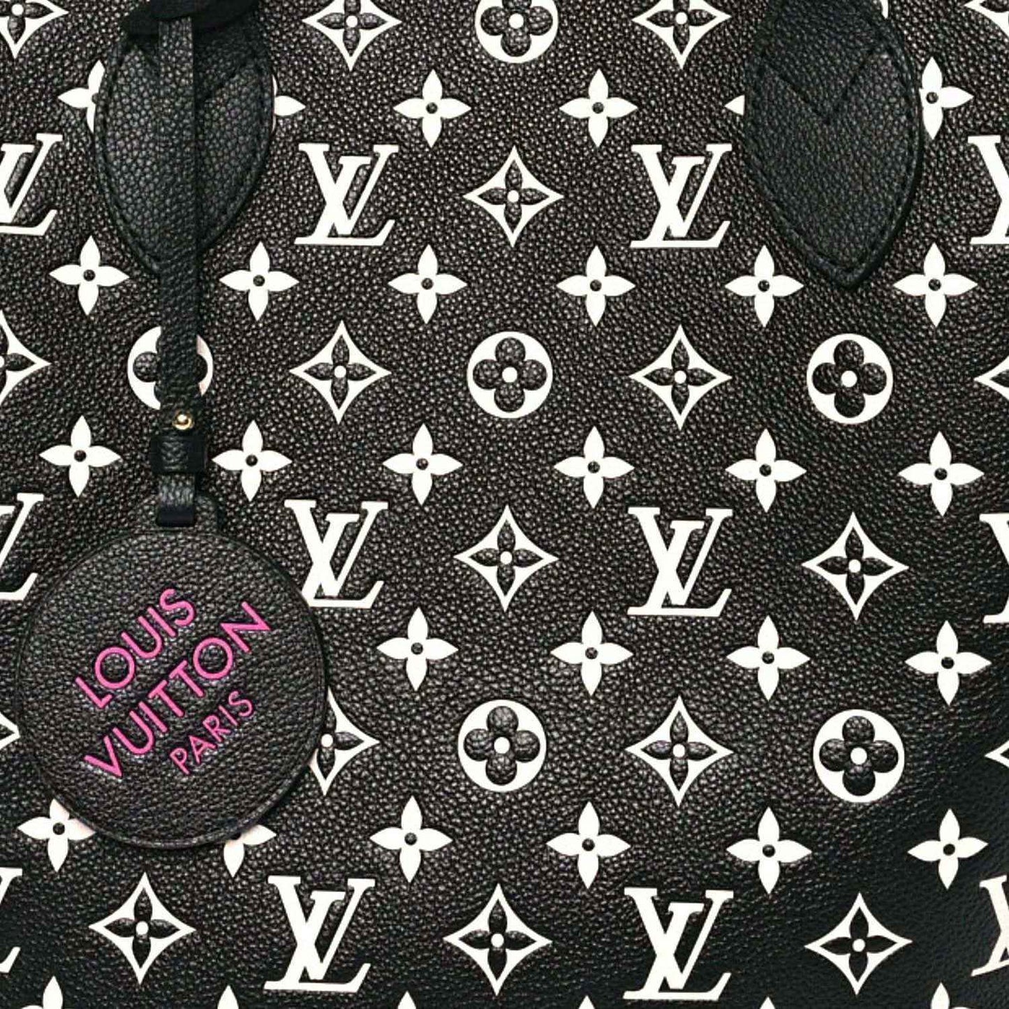 Monogram canvas tote panel with repeating LV motifs and a round branded charm