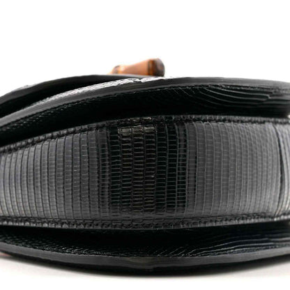 Top edge close-up of black mini bag with glossy trim and embossed texture