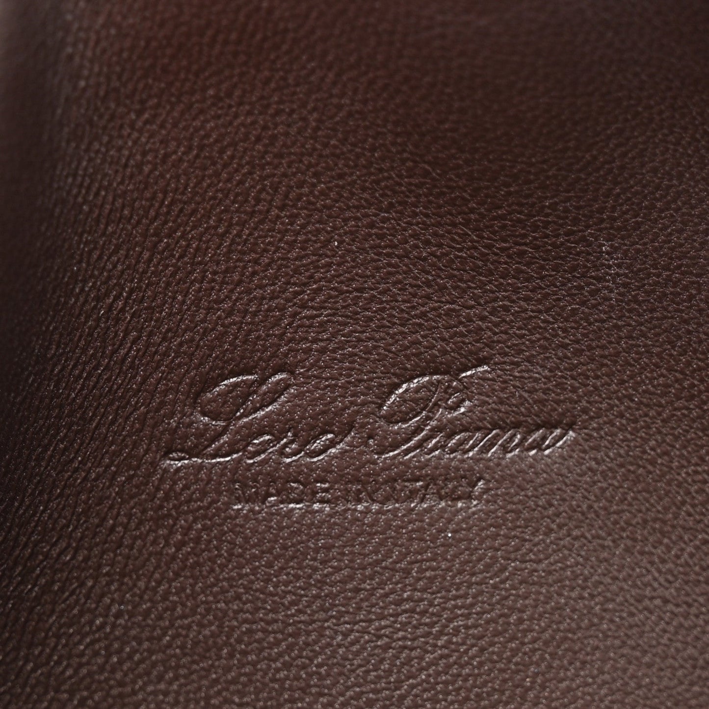 Loro Piana logo embossed on dark brown lizard leather pouch surface